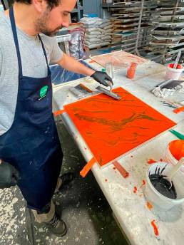 Artista creando effetto marmorizzato su tavola arancione.