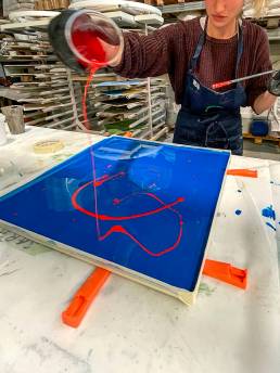Donna versa colore rosso su tela blu