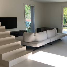 Soggiorno moderno con divano grigio e scale.
