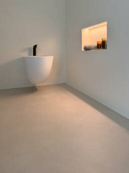 Bagno minimalista con lavabo sospeso e nicchia illuminata