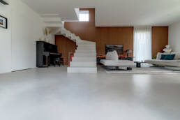 Soggiorno moderno con scala bianca e parete in legno