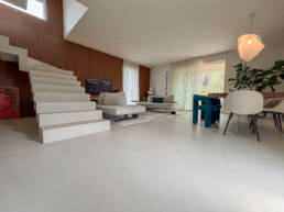 Soggiorno moderno con scala bianca e ampie vetrate