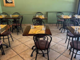 Sala ristorante con tavoli apparecchiati e sedie nere